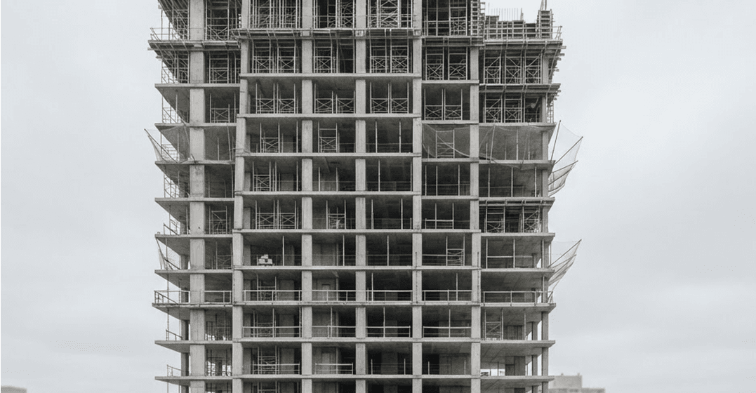 Concrete-framed tower under construction, with scaffolding and edge netting on the upper floors.